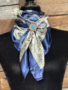 Decorative scarf with brooch on a mannequin against a wooden background